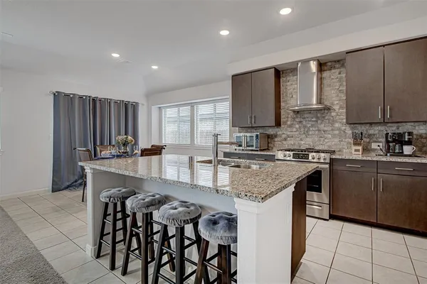 a kitchen with stainless steel appliances granite countertop a stove a sink a microwave a center island and a refrigerator