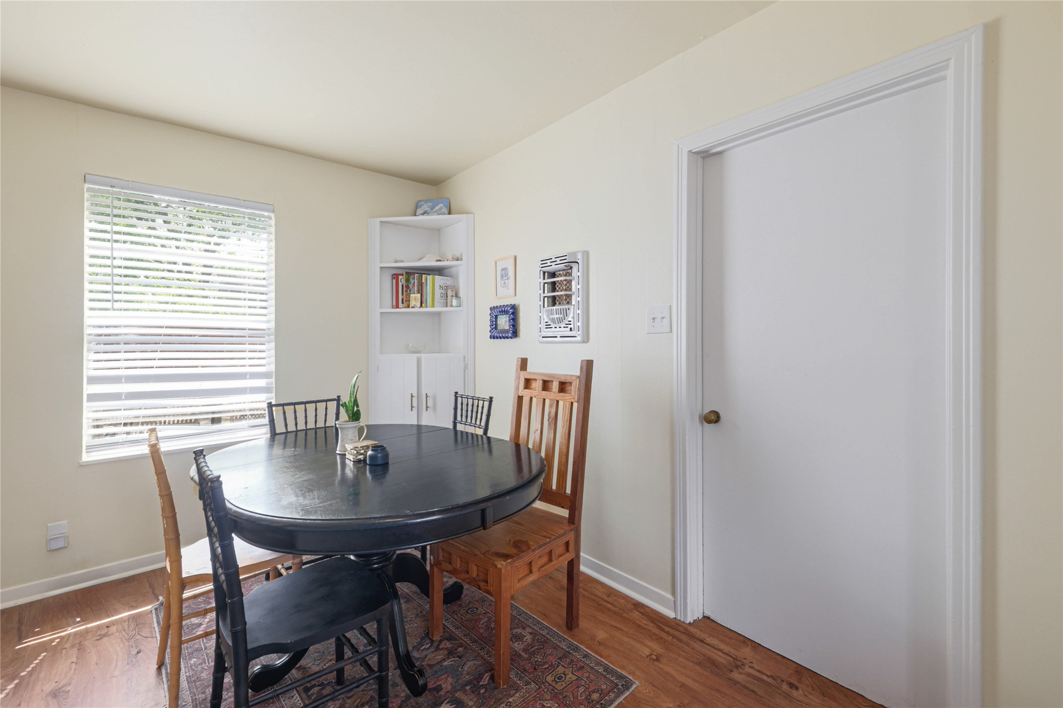 4607 Evans Avenue, Unit B Austin, TX 78751 - Photo 20 of 34 Dining area featuring wood-finish flooring, a corner built-in shelving unit, and a window with horizontal blinds