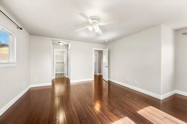 a view of an empty room with wooden floor and a window