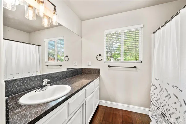 a bathroom with a granite countertop sink and a window