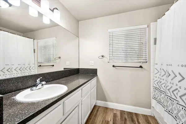 a bathroom with a granite countertop sink a mirror and a shower