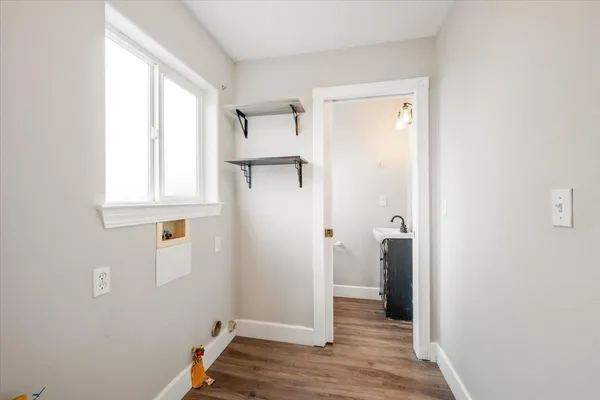 a view of hallway with window and wooden floor