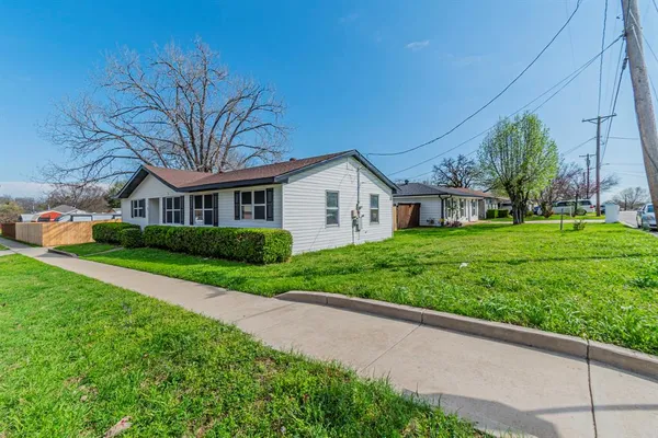 a view of house with a big yard and large trees