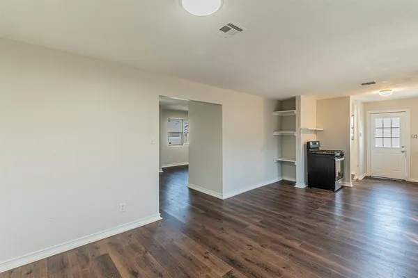 wooden floor in an empty room with a kitchen