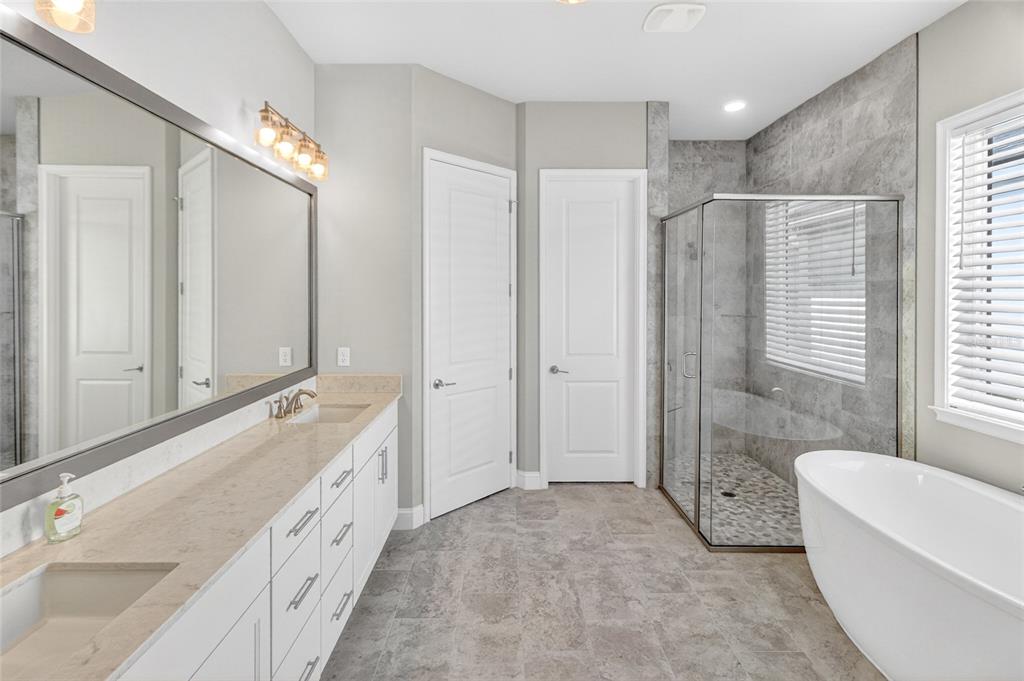 11992 Southwest 32nd Lane Gainesville, FL 32608 - Photo 12 of 29 a spacious bathroom with a double vanity sink a large mirror and a bathtub