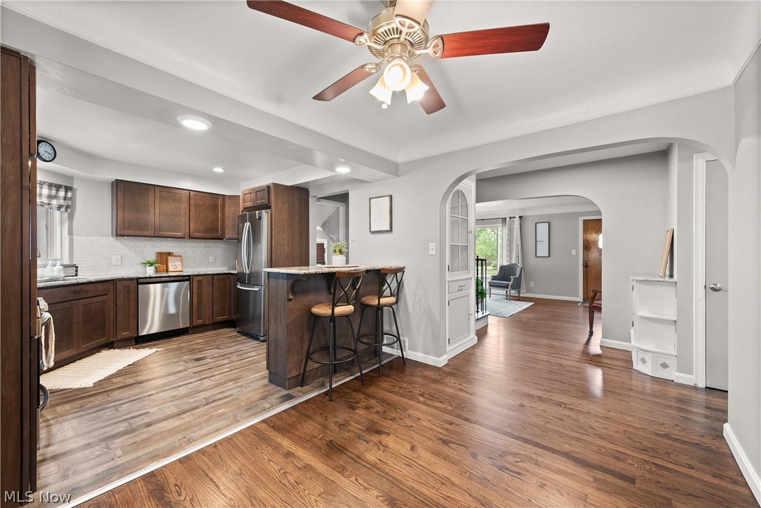 21779 Eaton Road Cleveland, OH 44126 - Photo 13 of 46 Kitchen featuring ceiling fan, tasteful backsplash, a breakfast bar area, wood-type flooring, and appliances with stainless steel finishes
