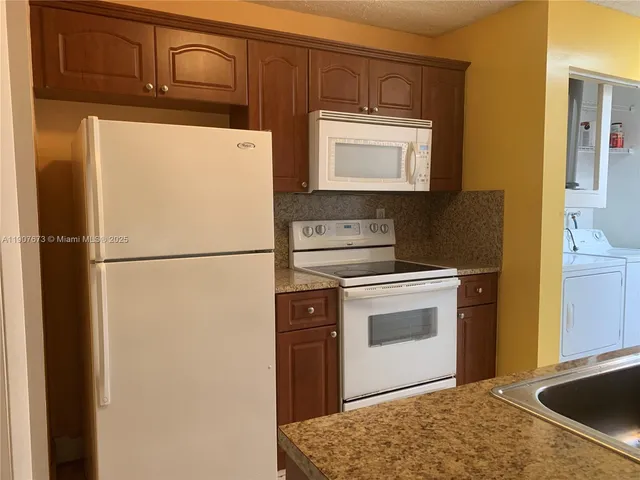 a kitchen with stainless steel appliances granite countertop a refrigerator a stove a sink and a microwave