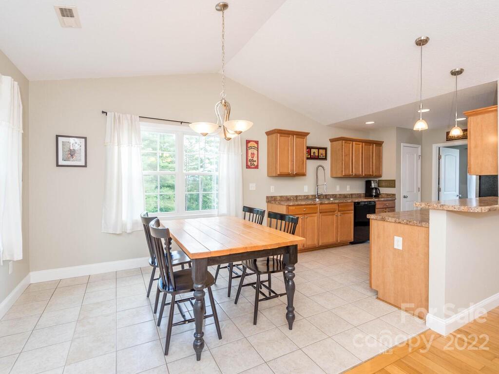 243 Scarlett Ridge Drive Marshall, NC 28753 - Photo 16 of 36 a kitchen with a dining table chairs and white cabinets