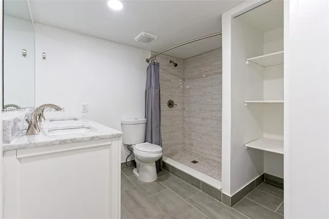 a bathroom with a granite countertop sink toilet and shower