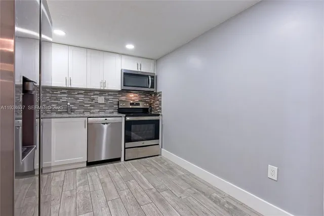 a kitchen with stainless steel appliances granite countertop a stove a sink and a refrigerator