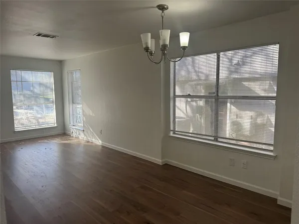 an empty room with wooden floor mirror and windows