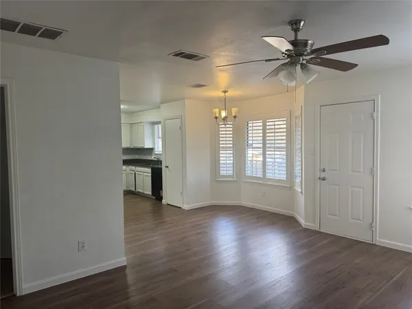 an empty room with wooden floor fan and windows