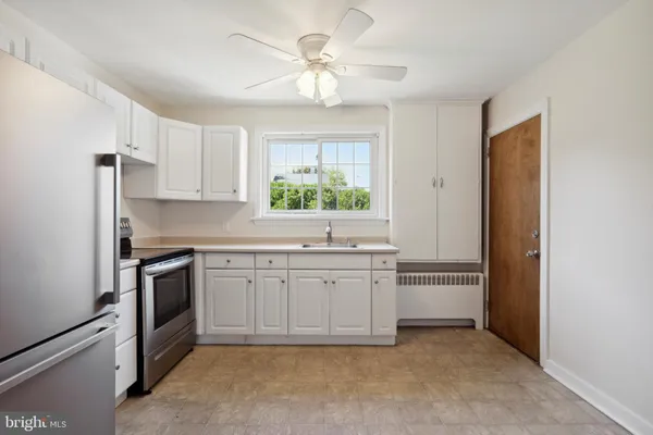 a kitchen with white cabinets appliances and a window