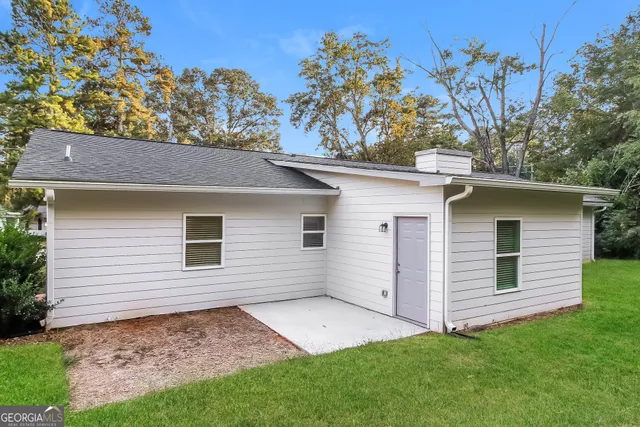 a view of a backyard with plants and large tree