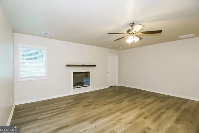 an empty room with a fireplace and a ceiling fan