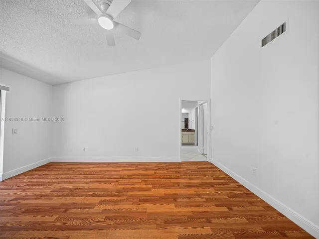 a view of an empty room with kitchen and a window