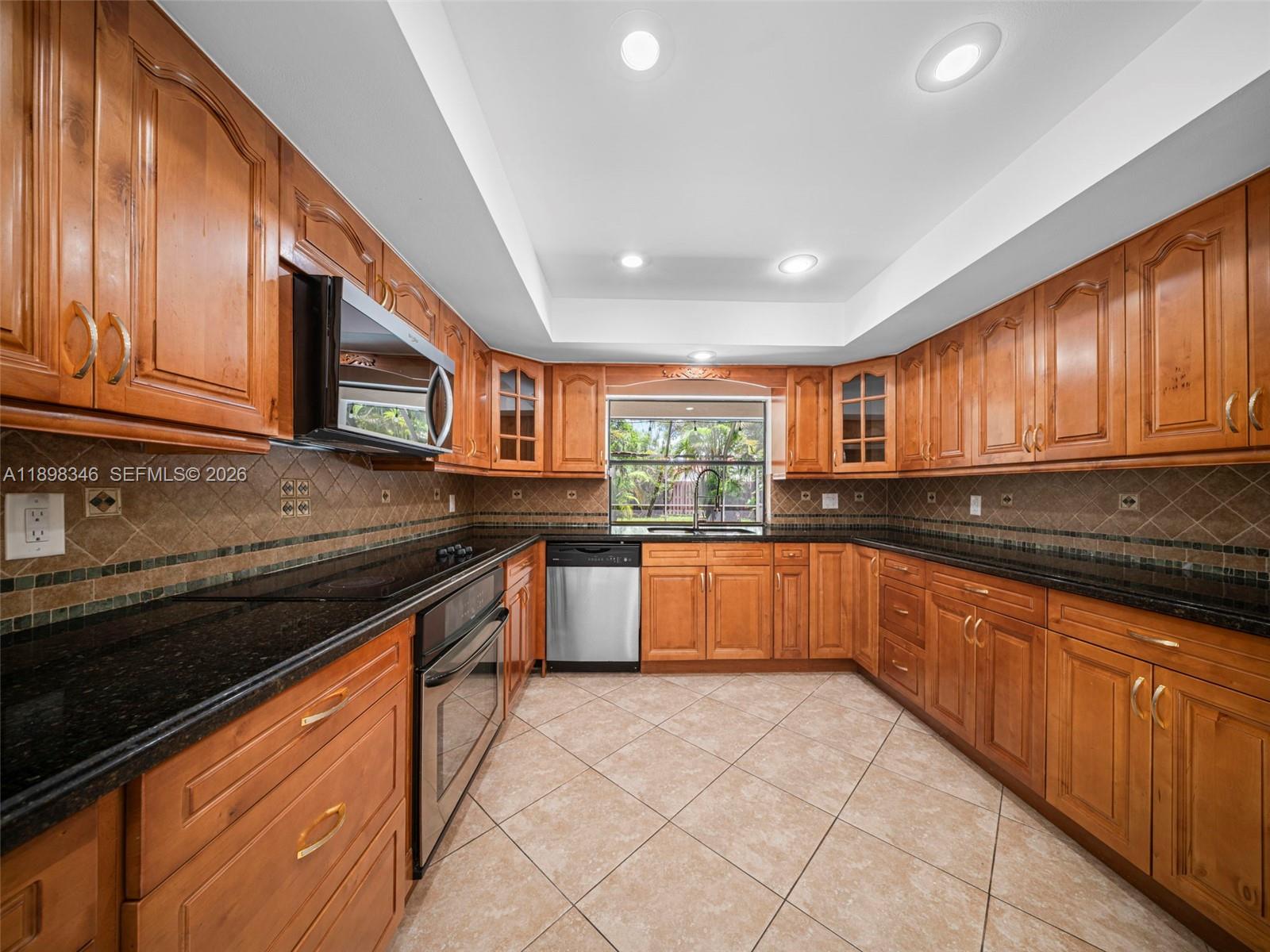 15531 Southwest 54th Terrace Miami, FL 33185 - Photo 30 of 61 a kitchen with stainless steel appliances granite countertop wooden cabinets a sink dishwasher stove and granite countertops with cabinets