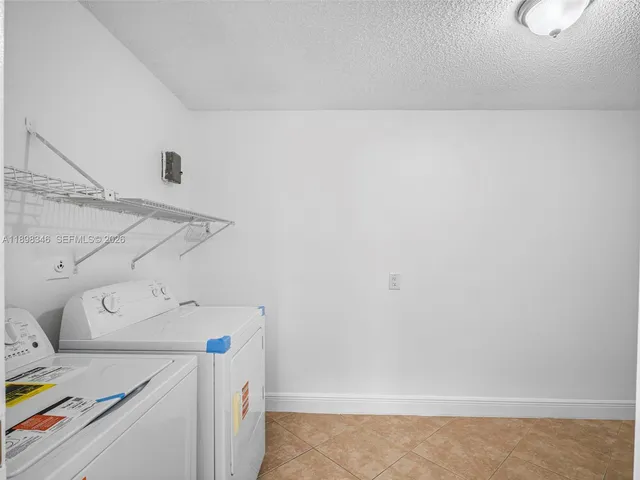 a view of an empty room with kitchen and a window