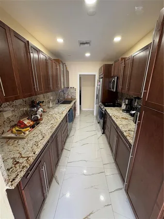 a large kitchen with kitchen island granite countertop wooden cabinets a sink and stainless steel appliances