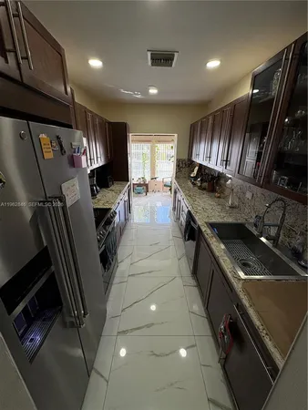 a kitchen with stainless steel appliances granite countertop a sink a stove and a refrigerator