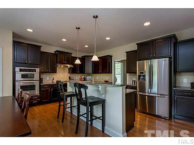 13028 Saxon Way Raleigh, NC 27613 - Photo 3 of 21 a kitchen with stainless steel appliances kitchen island granite countertop a refrigerator and a stove top oven