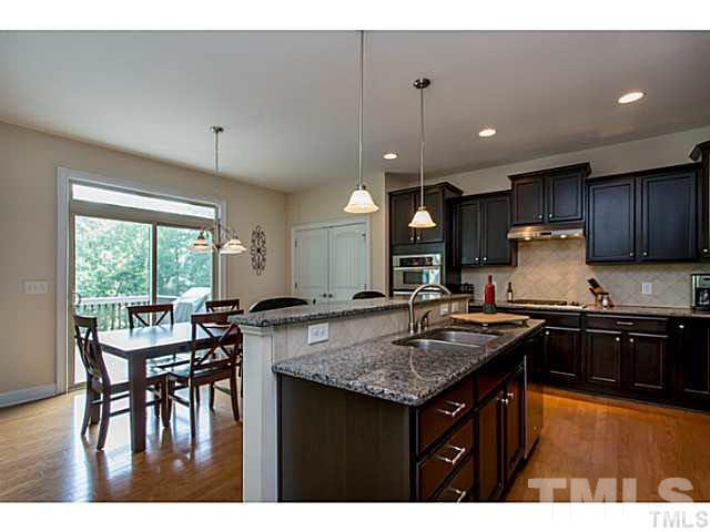 13028 Saxon Way Raleigh, NC 27613 - Photo 6 of 21 a kitchen with a stove a kitchen island a dining table and chairs