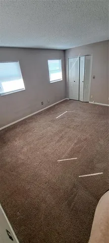 a view of an empty room with window and closet area