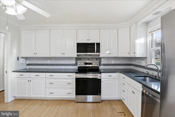 a kitchen with granite countertop white cabinets and appliances