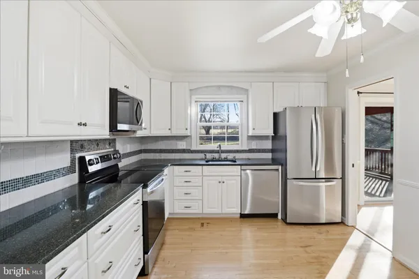 a kitchen with stainless steel appliances granite countertop a refrigerator a stove a sink and a microwave