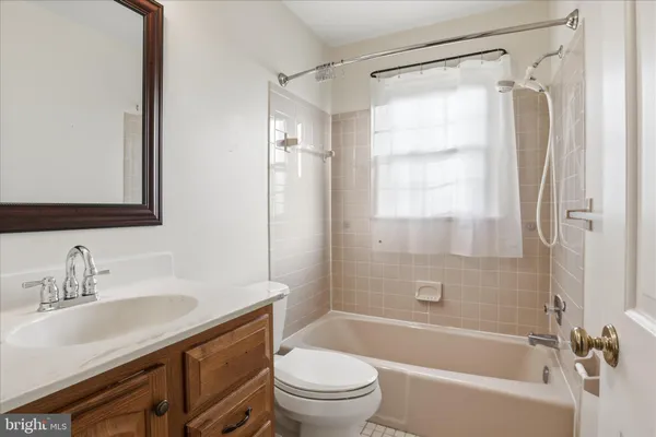 a bathroom with a granite countertop bathtub shower sink vanity mirror and toilet
