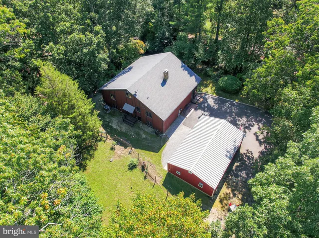 an aerial view of a house with yard and trees in the background