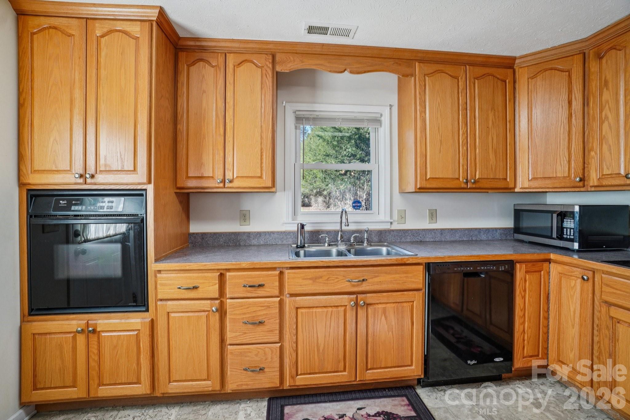 511 Oak Grove Road Flat Rock, NC 28731 - Photo 16 of 38 a kitchen with granite countertop wooden cabinets stainless steel appliances a sink and a window