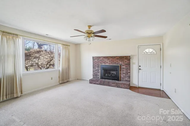 an empty room with chandelier fan and windows