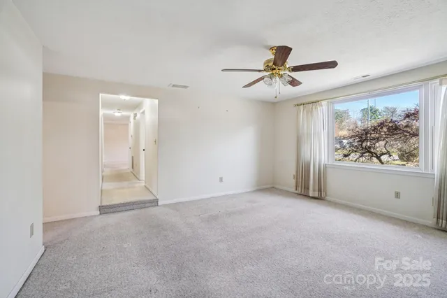 a view of an empty room with a fireplace and a window