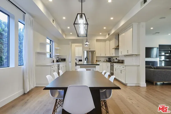a large kitchen with kitchen island a dining table chairs and white cabinets