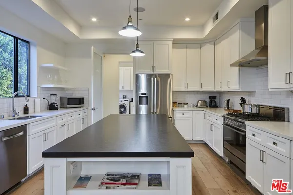 a kitchen with kitchen island a counter space a sink stainless steel appliances and cabinets