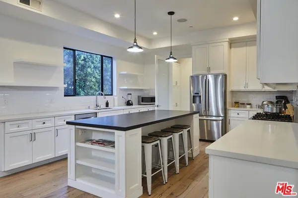 a kitchen with a sink a center island stainless steel appliances and cabinets