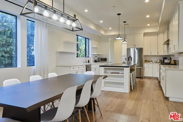 a kitchen with a dining table chairs stainless steel appliances and cabinets