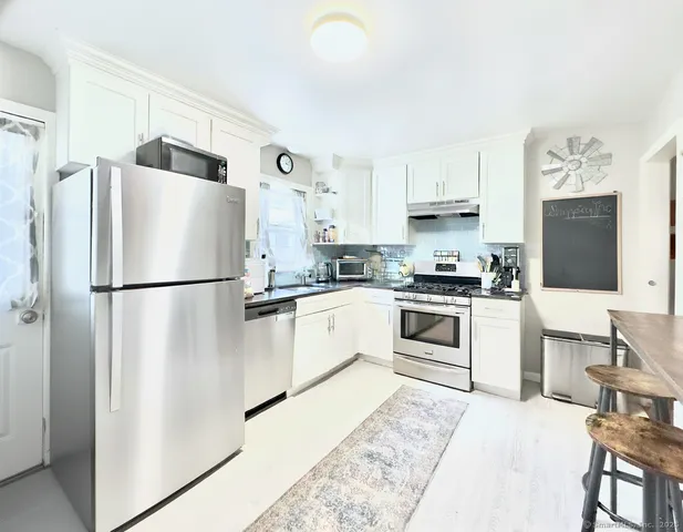 a kitchen with stainless steel appliances a refrigerator sink and white cabinets