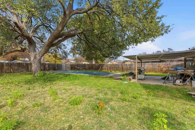 a view of a yard with table and chairs under an umbrella