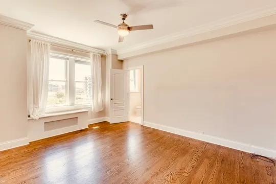 an empty room with wooden floor chandelier fan and windows