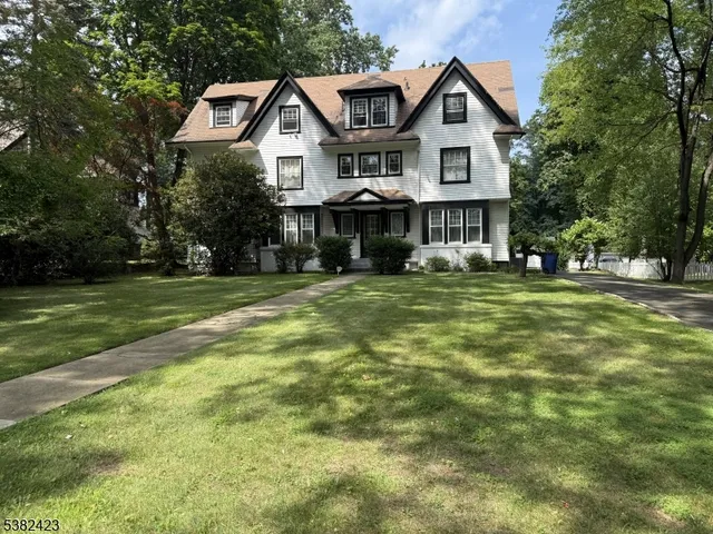 a front view of a house with a yard and trees