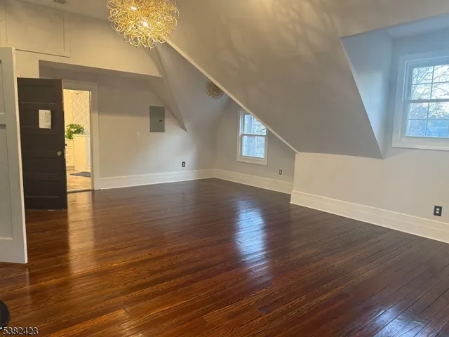 an empty room with wooden floor and a refrigerator