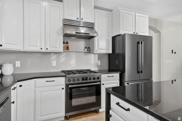 14738 Tangle Hill Road Herriman, UT 84096 - Photo 19 of 66 Kitchen featuring white shaker-style cabinetry, dark stone countertops, stainless steel range with hood, and a black French door refrigerator