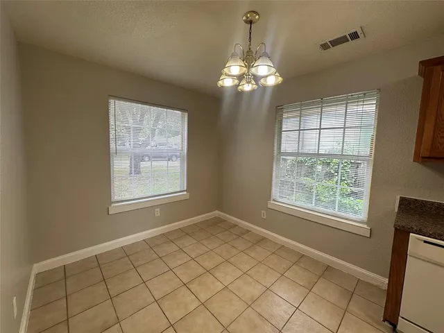 en empty room with windows and chandelier fan