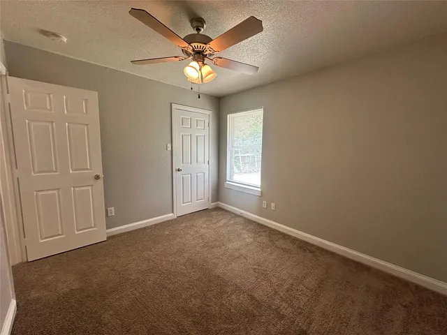 an empty room with a ceiling fan and a window