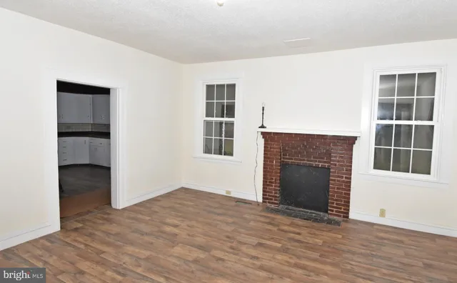 an empty room with windows and fireplace
