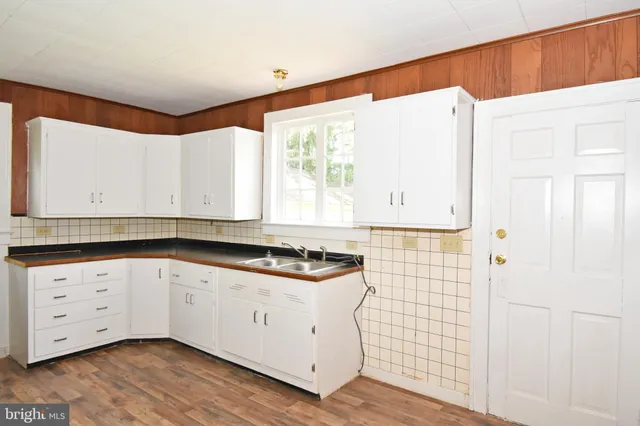 a kitchen with granite countertop white cabinets and a sink
