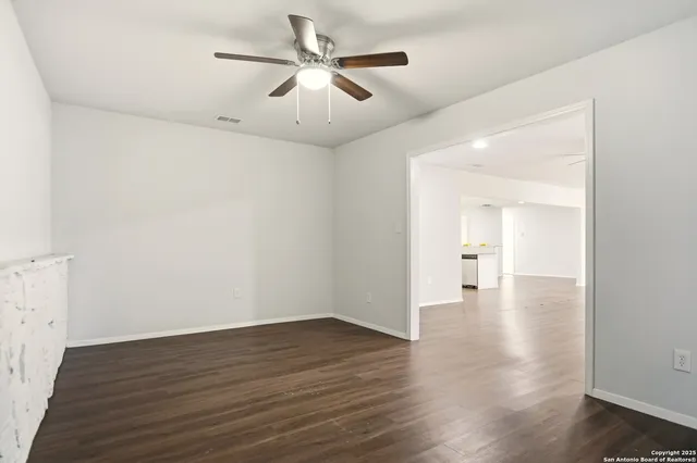 an empty room with wooden floor and ceiling fan