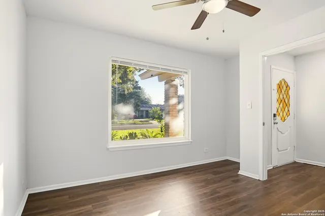 an empty room with wooden floor cabinet and windows